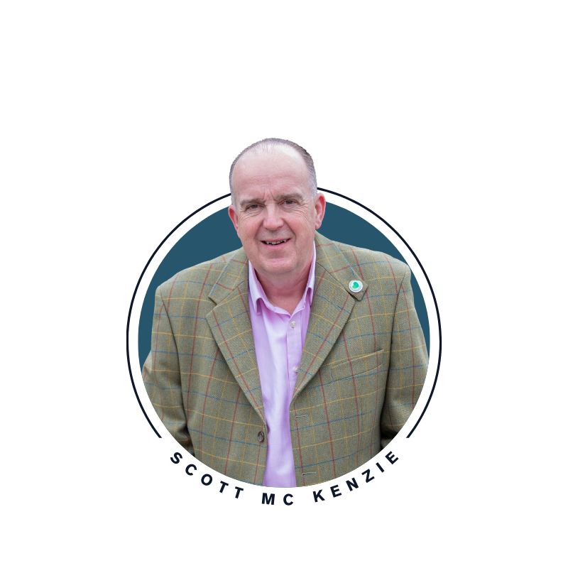 Portrait of Scott McKenzie wearing a checked blazer and light shirt, smiling.